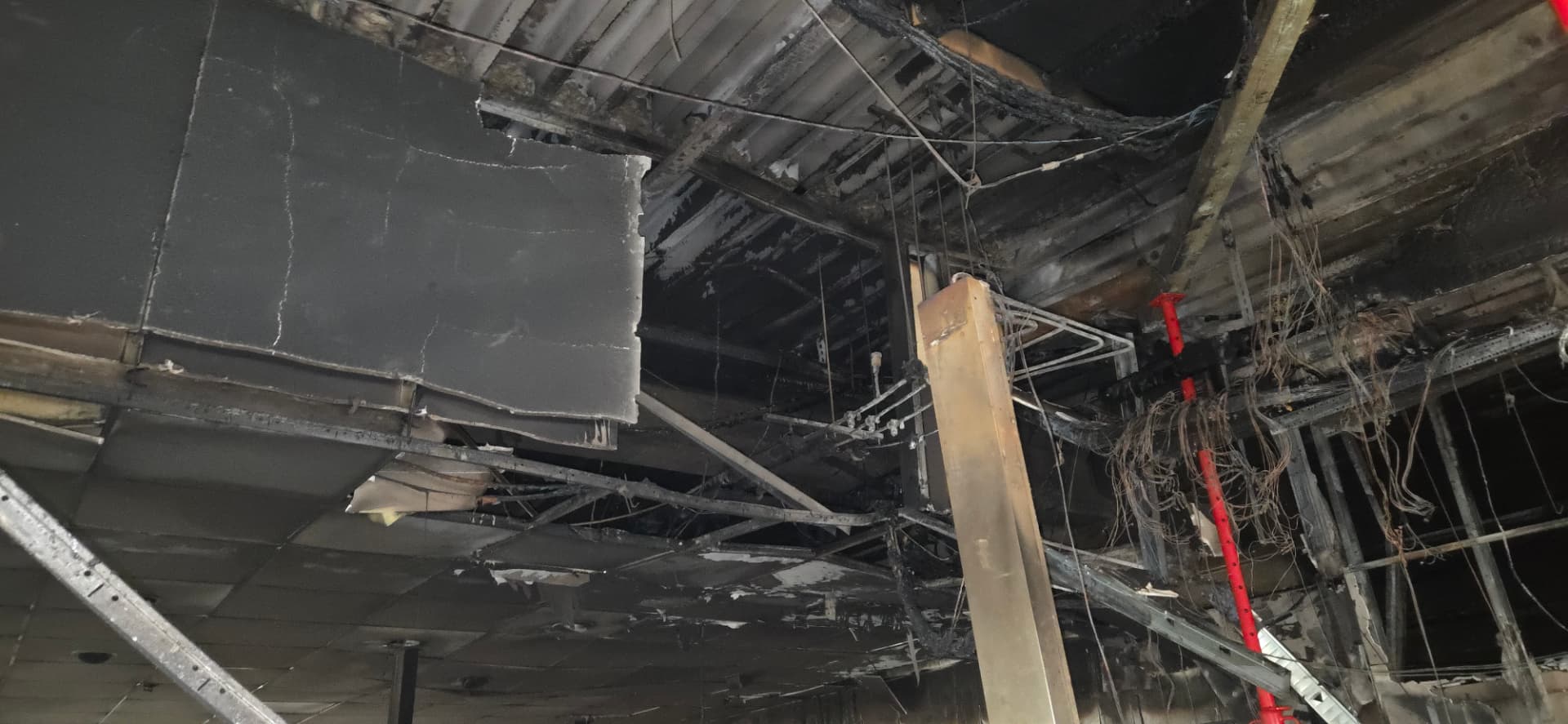 Brand- og sodskadede tagplader og nedhængt loft med rød stempelstøtte i butikken i Aabybro